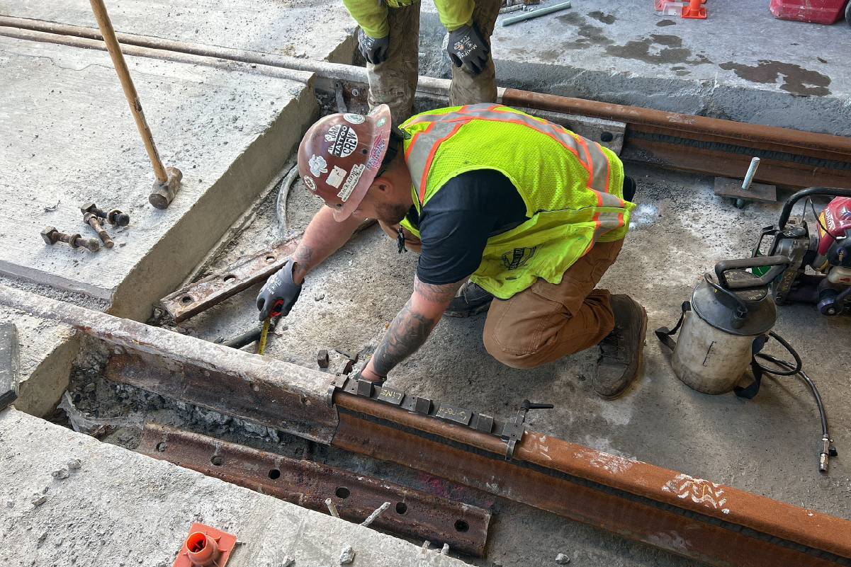 crew member using measuring tape next to rail