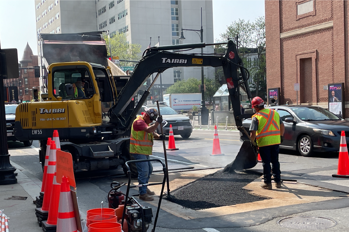 Workers pave a section of Massachusetts Ave following ductbank installation