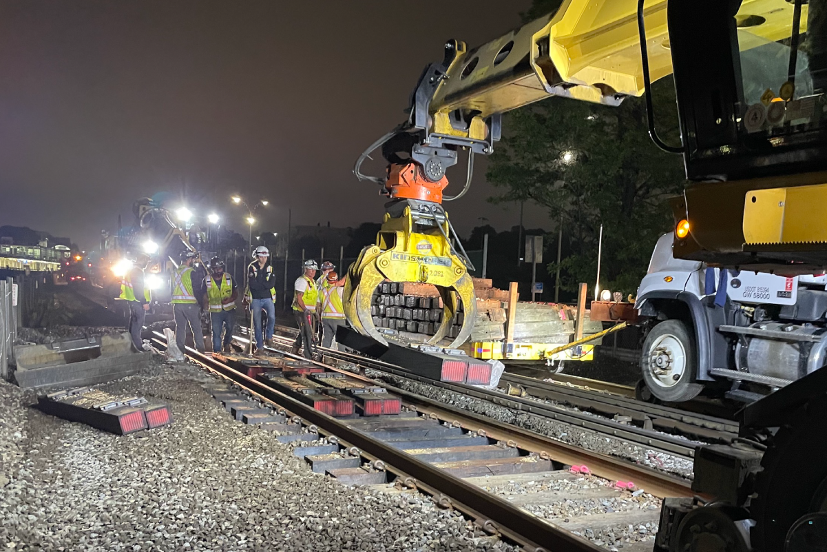 crews working on tracks at night under bright floodlights