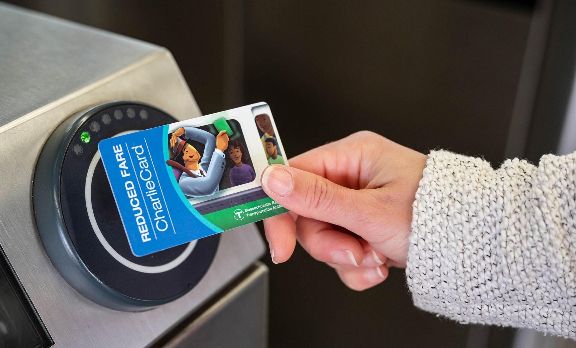 Rider holding a reduced fare CharlieCard to a fare gate reader