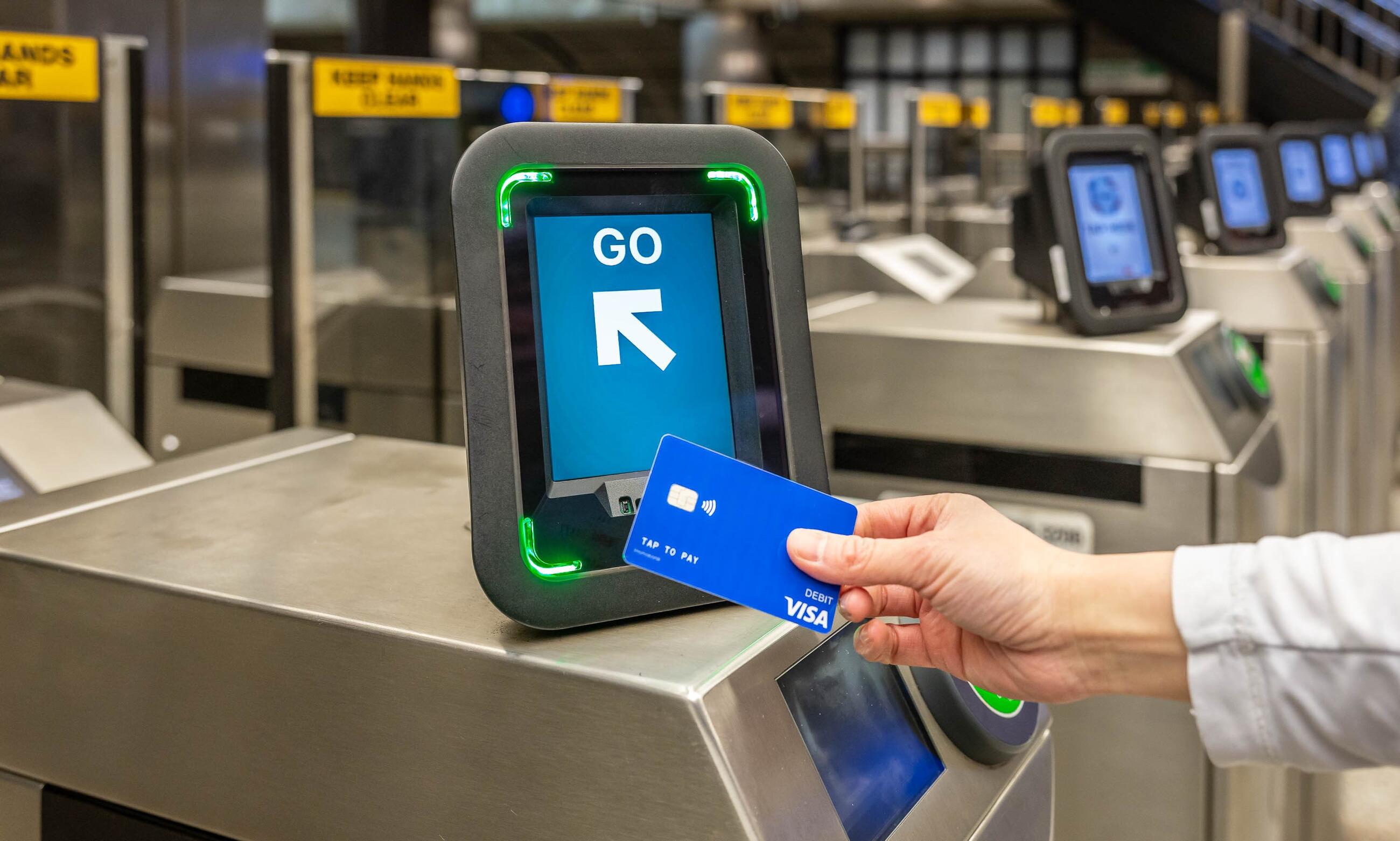 Rider tapping Visa card on Charlie reader that reads GO on a green screen at fare gate