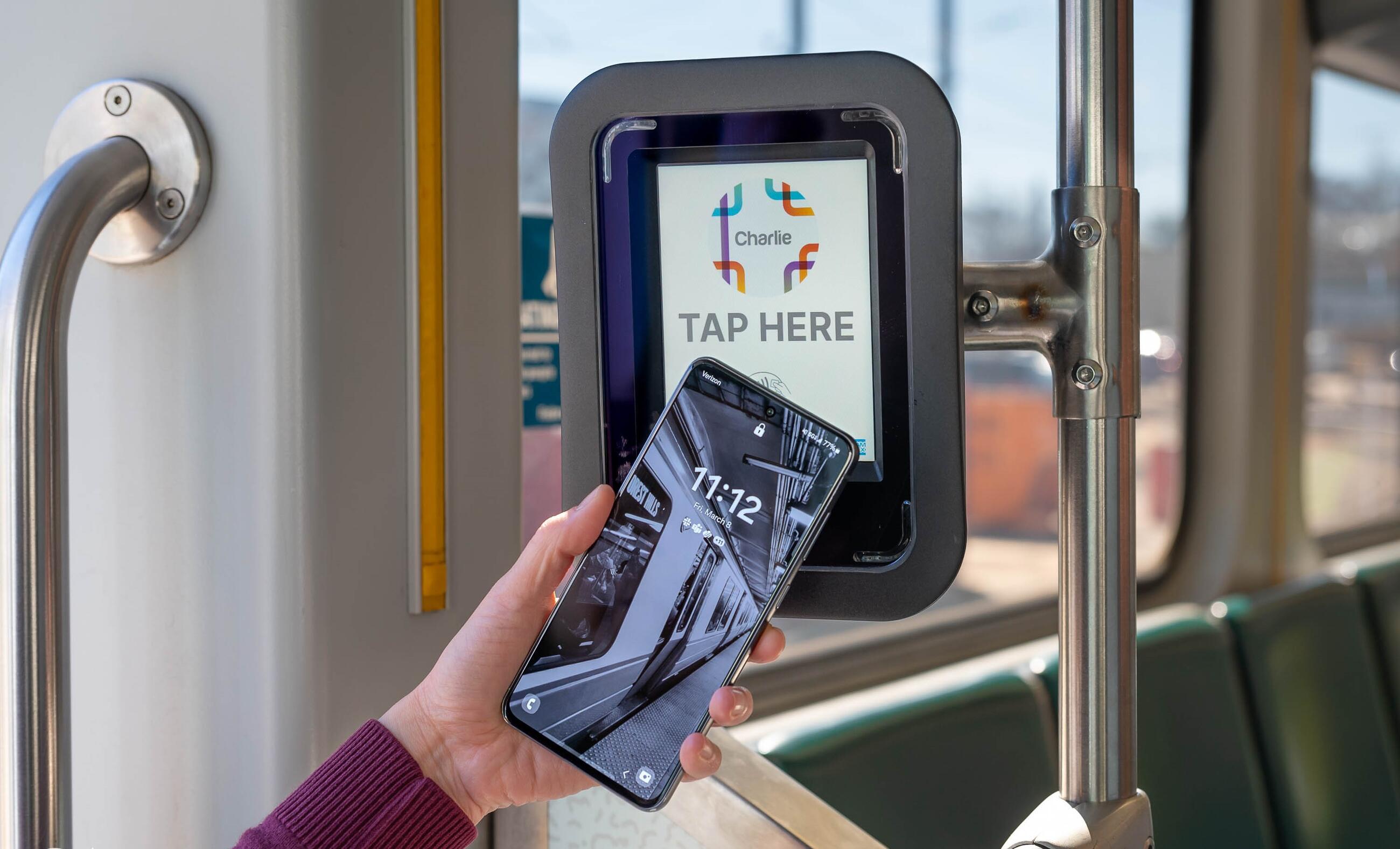 Rider tapping phone on Green Line Charlie reader that reads tap here