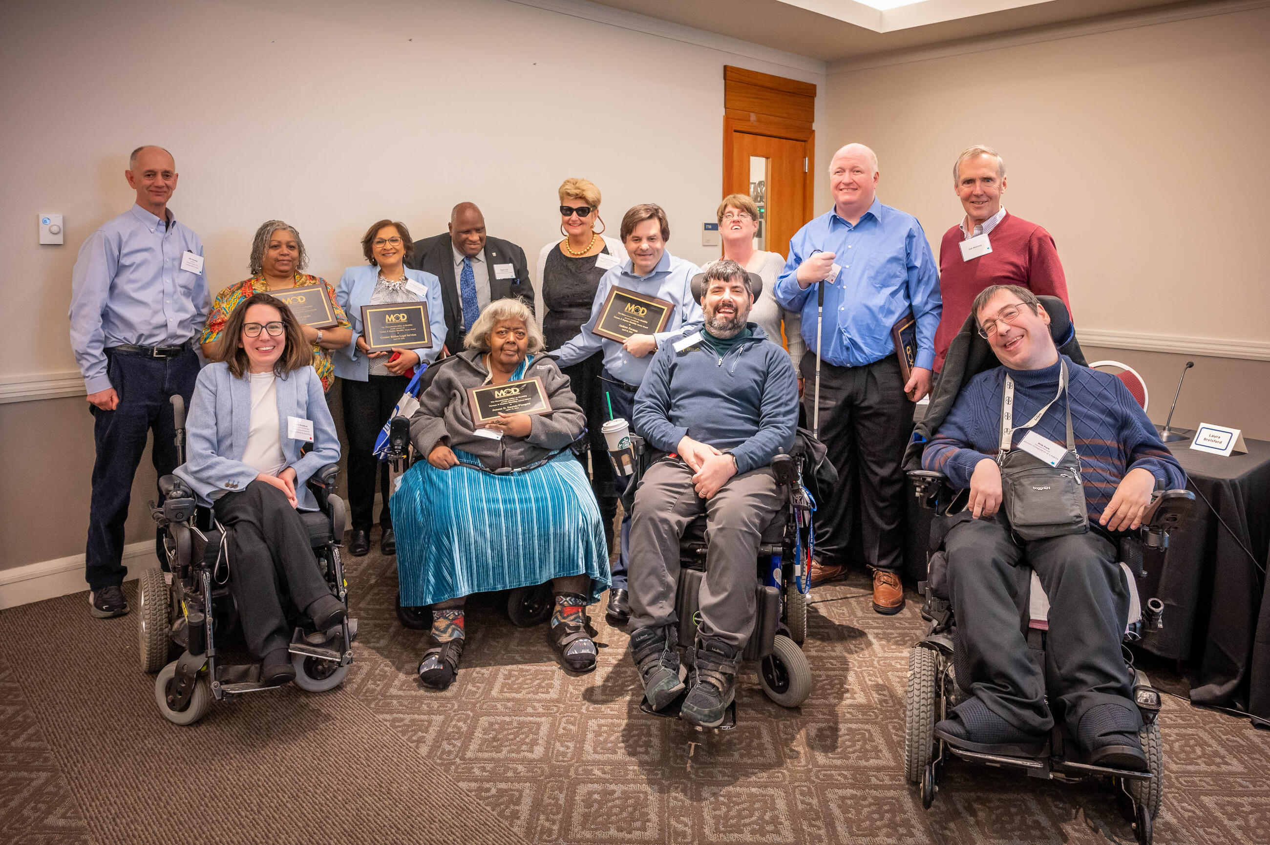 A group of people holding plaques with their awards for improving accessibility in Massachusetts.