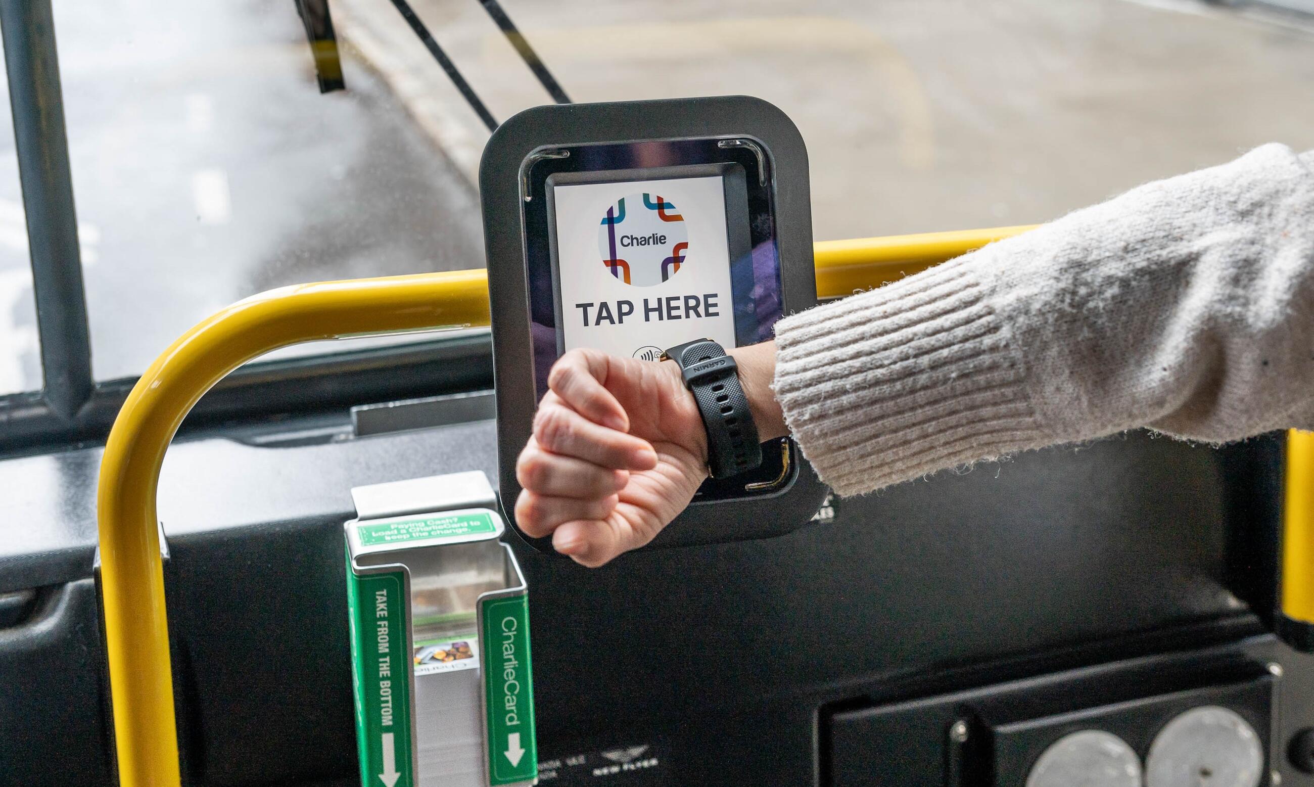  Rider tapping contactless watch on bus reader that reads tap here