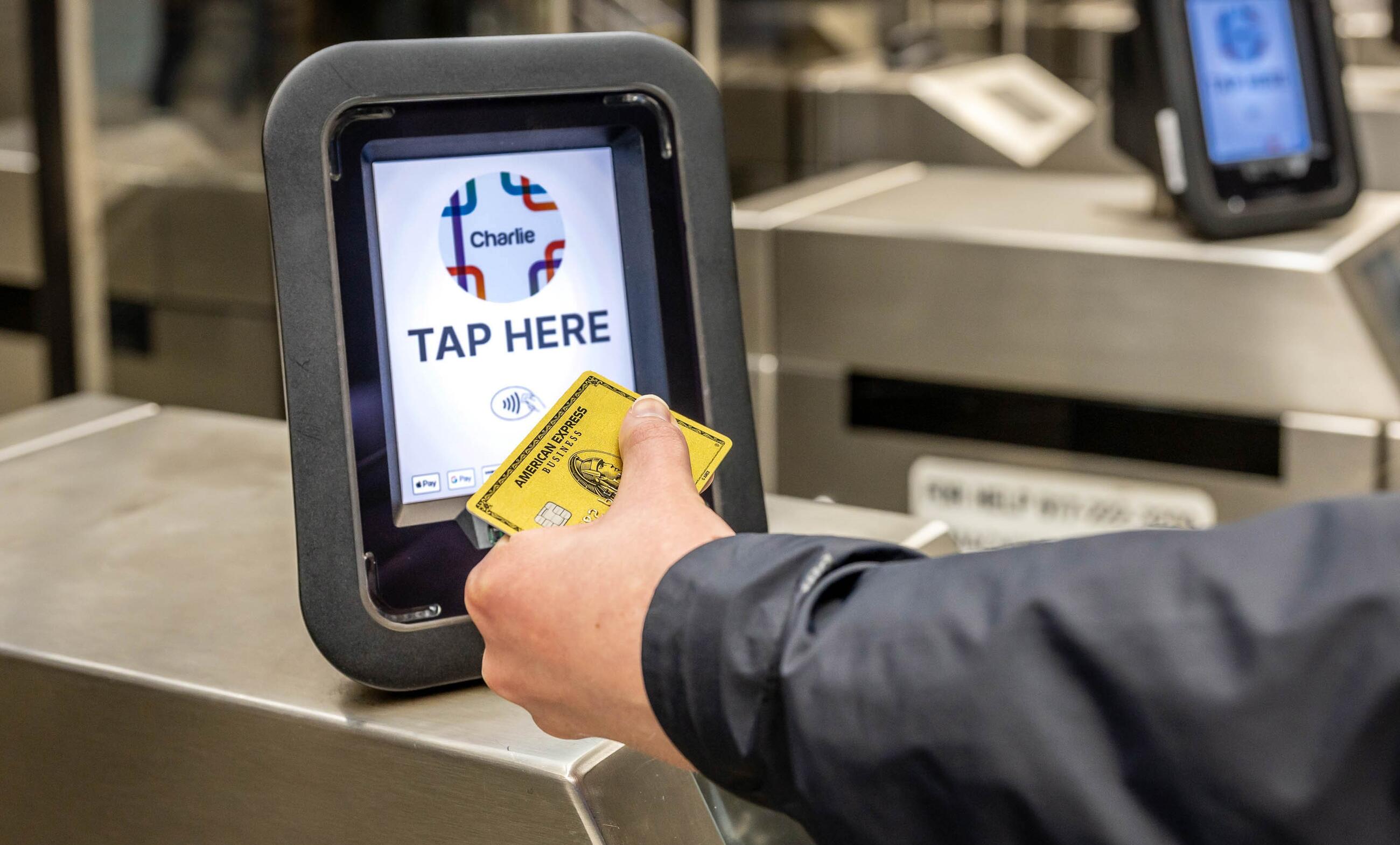 Rider tapping AMEX contactless card on a Charlie reader that reads tap here at fare gate