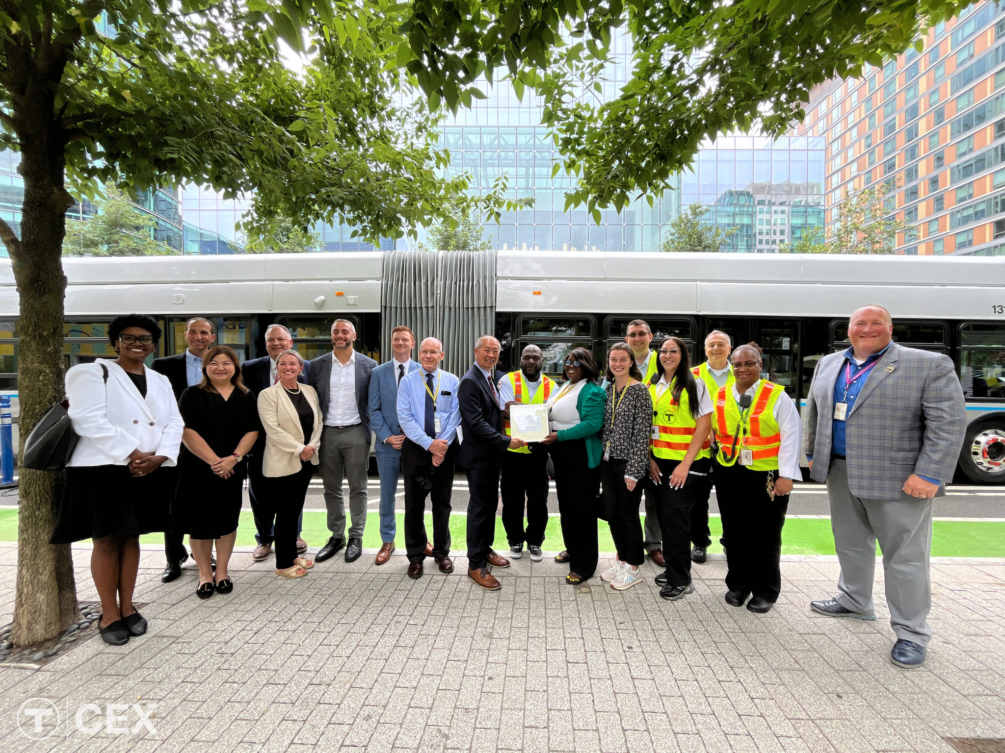 A dozen individuals stand in front of a bus on a sidewalk