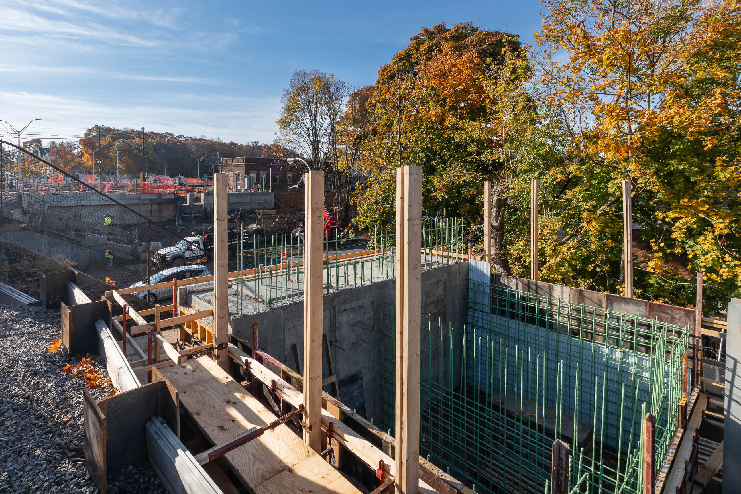 A large ditch in the work zone has grids of green rebar and wooden support beams on the side