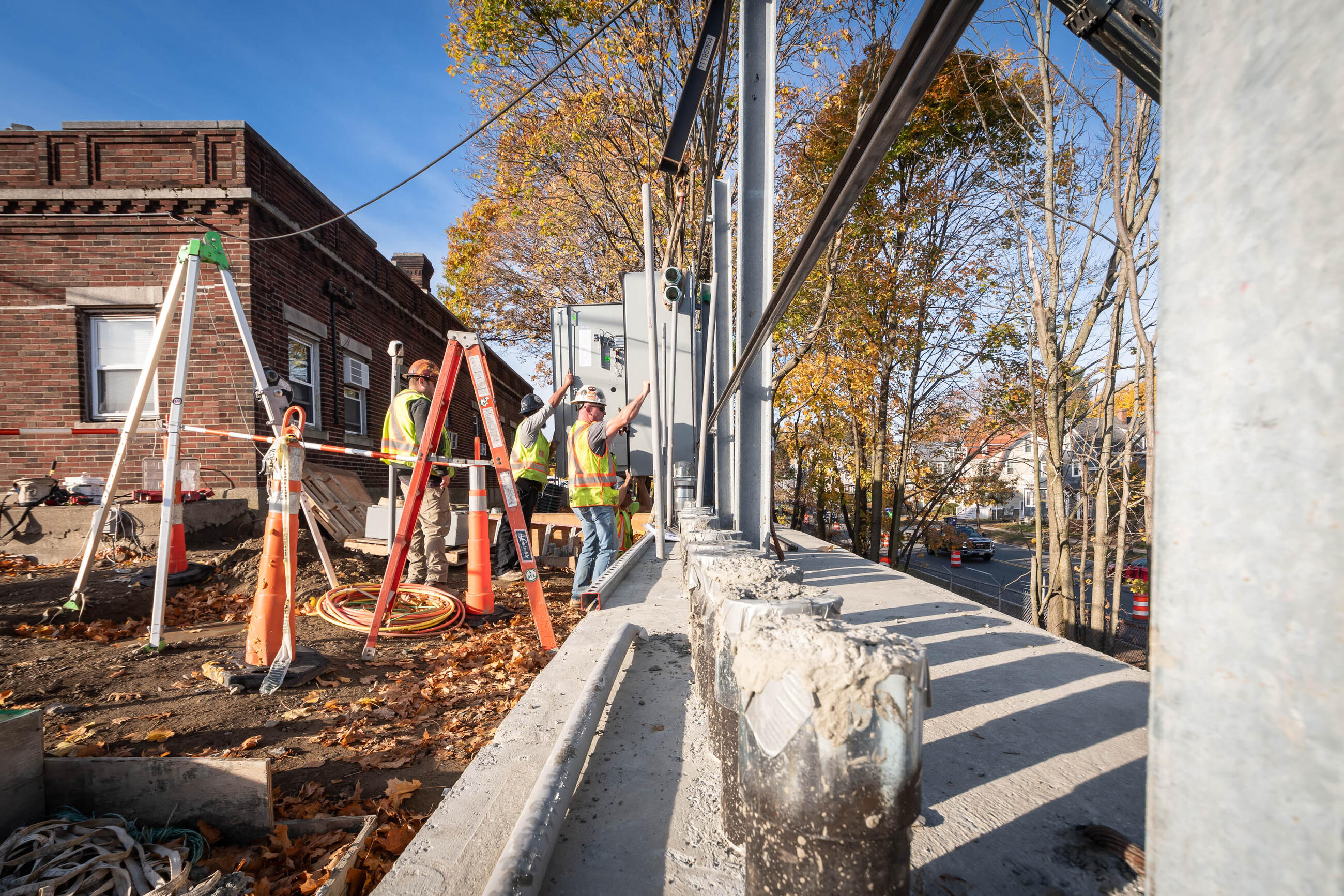 Three construction workers guide steel bars and piles into place for a new wall