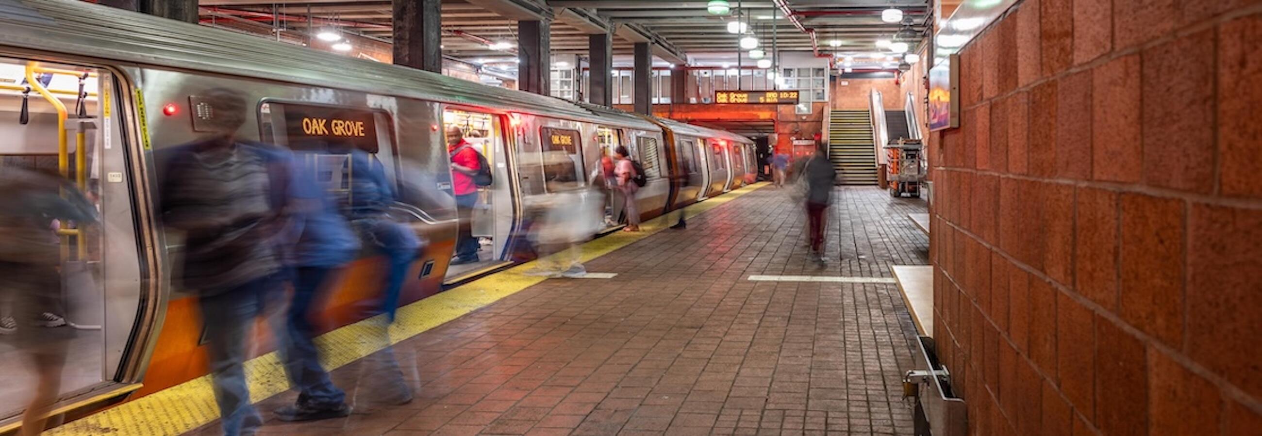 Riders board and exit an Orange Line Oak Grove train at the station 