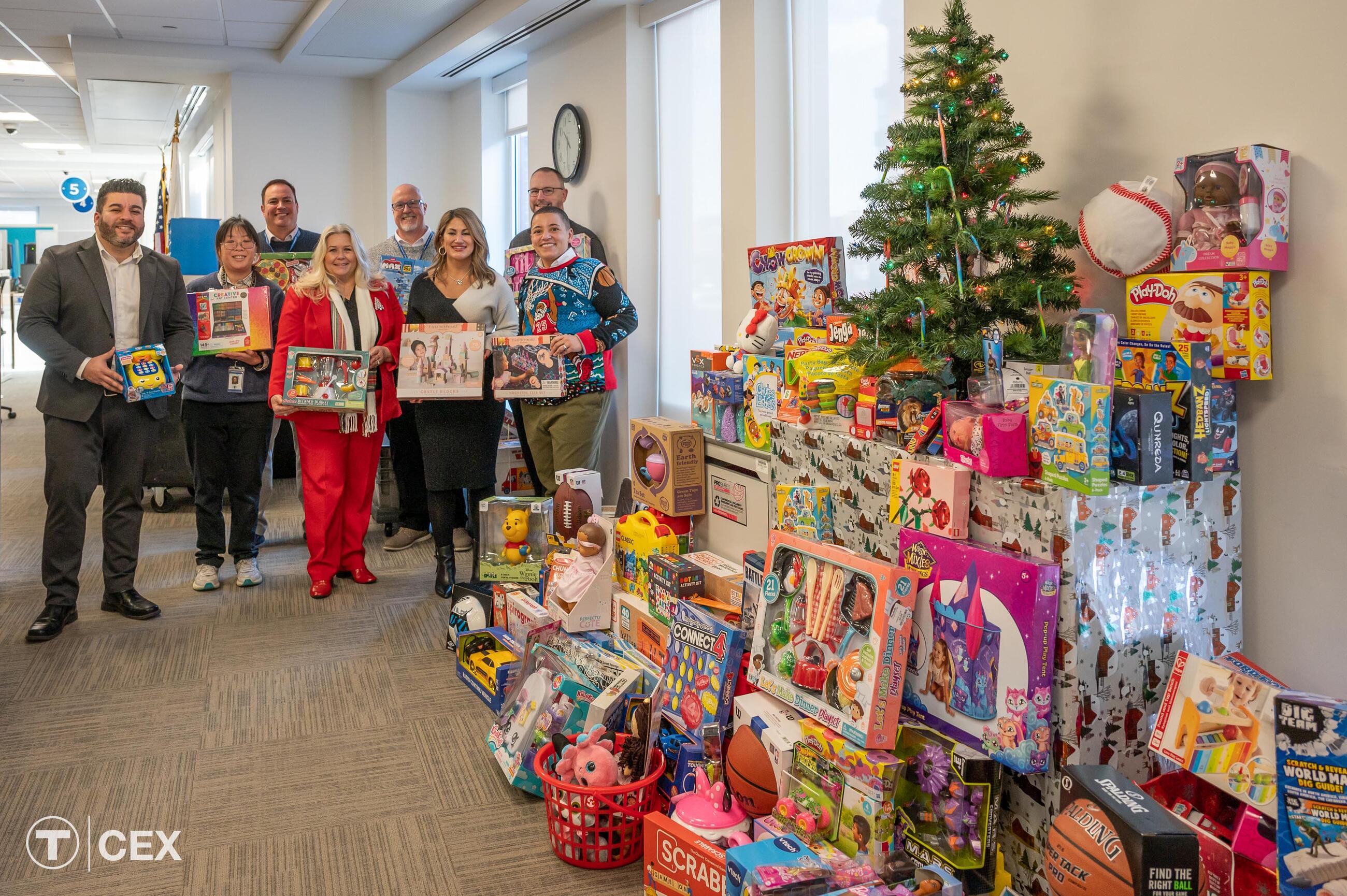 Boston RMV staff joined Transportation Secretary and CEO Monica Tibbits-Nutt with the many gifts donated as part of the Fill-a-Bus with Gifts holiday drive this year. Complimentary photo by the MBTA Customer and Employee Experience Department.