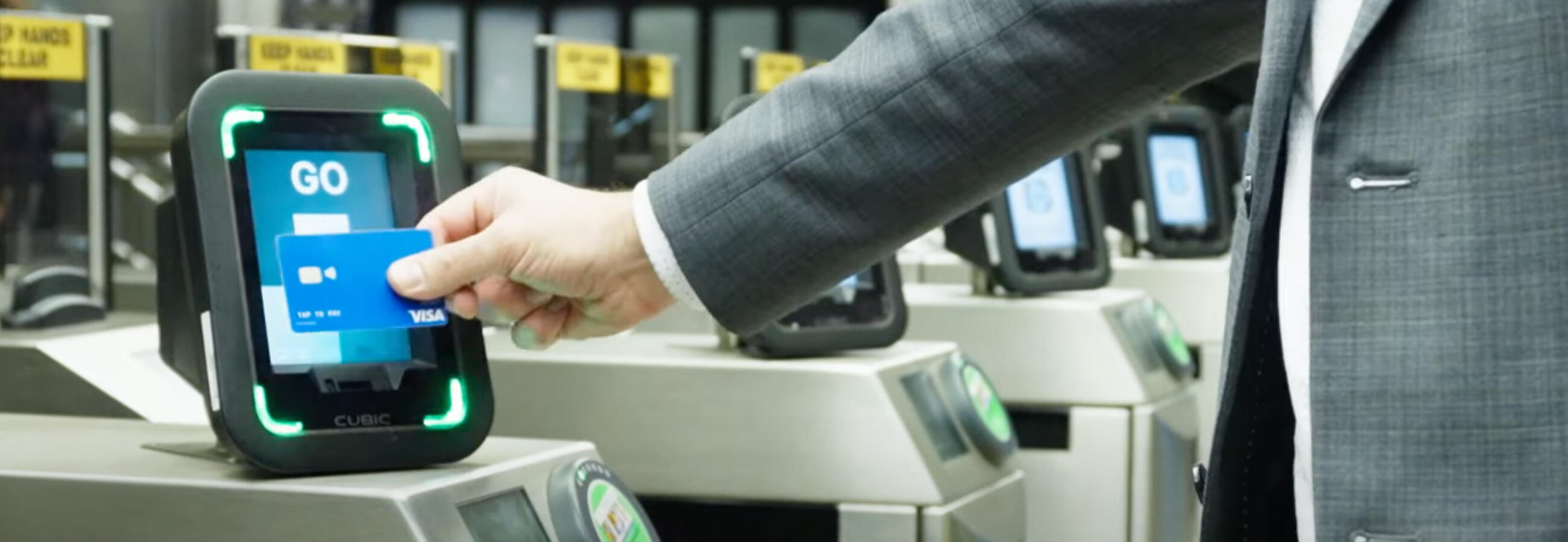 Hand tapping a card at a reader on a fare gate