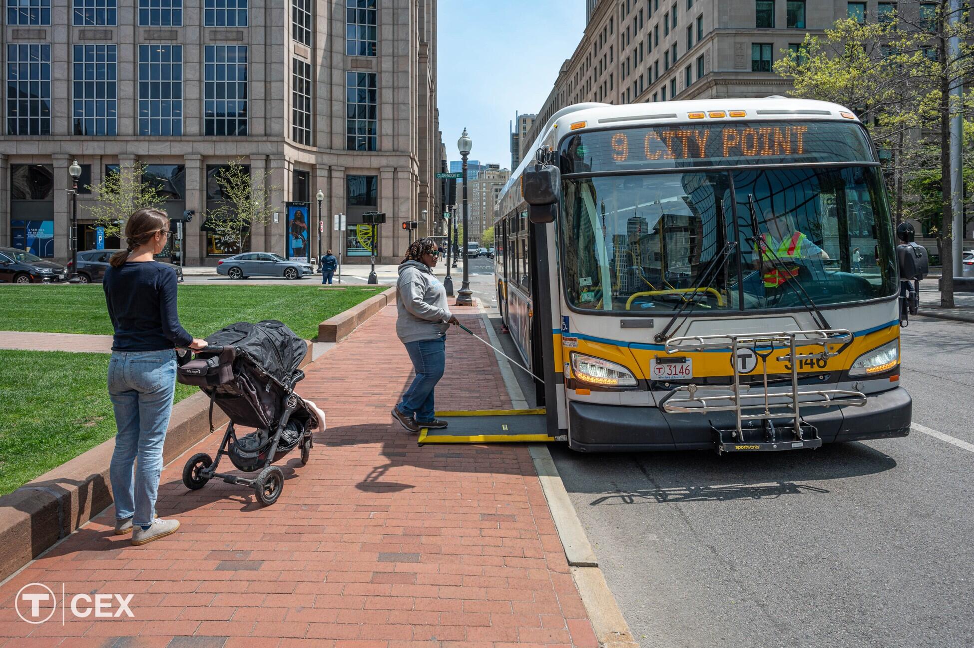 An MBTA bus pulls up to a sidewalk curb so it can deploy its ramp, which allows riders to safely board.