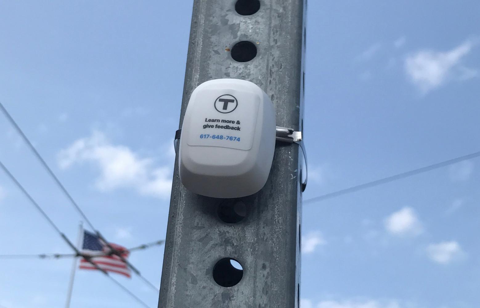Bluetooth beacon attached to the metal post of a bus stop sign