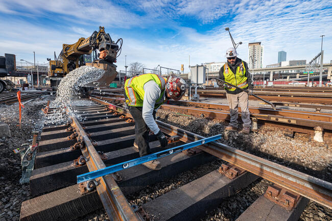Two personnel in personal protective equipment (PPE) perform rail work at Cabot Yard