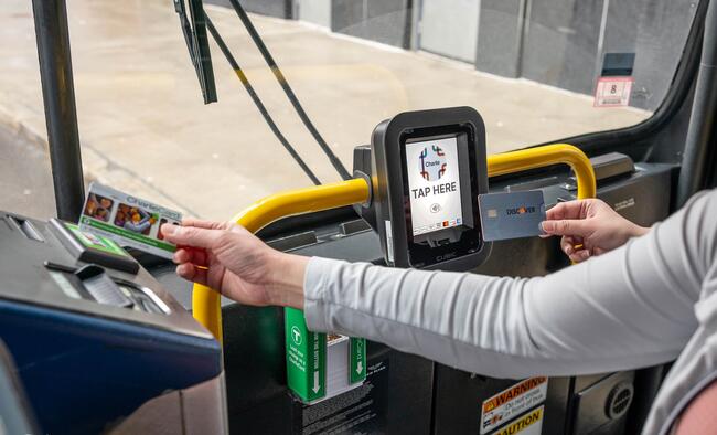 Two riders at bus entryway one tapping their CharlieCard on the farebox and another tapping their contactless card on the Charlie reader to the right of the fare box