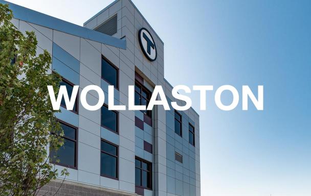 The facade of the newly rebuilt Wollaston Station, with white text overlaid that reads "Wollaston"