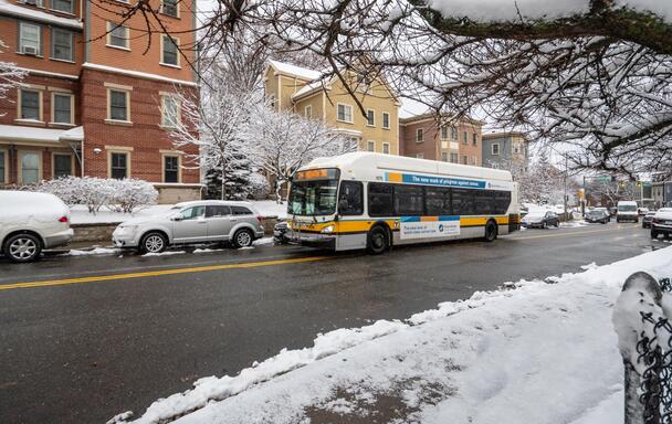 Route 39 bus travels inbound to Heath St on a cleared road, while snow is on cars and the gournd.