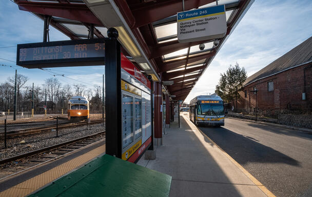a mattapan trolley to the left of Mattapan station platform and a bus to the right of the platform, both appear to be arriving at the same time