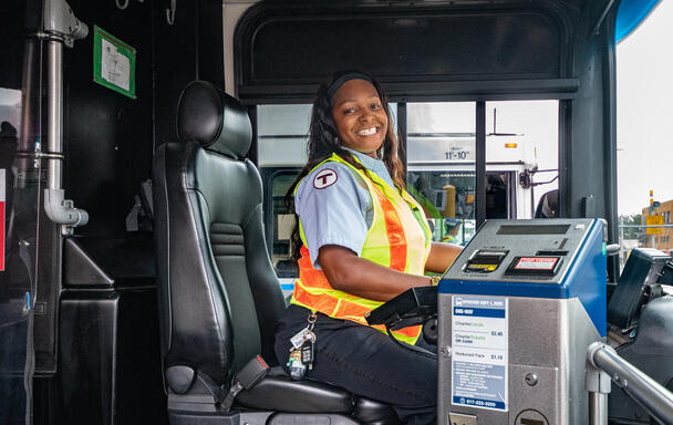A bus operator is seated at the front of an MBTA bus