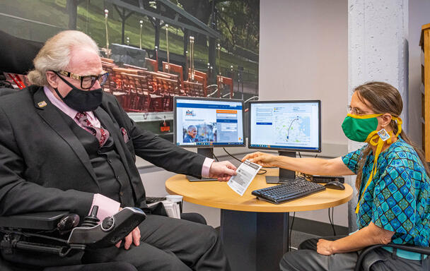 Rider being helped at the mobility center in front of a table with two computers