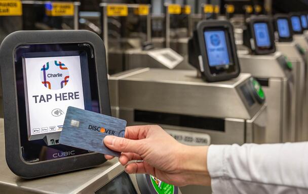 a Discover card being tapped on a contactless reader that says "Tap Here"