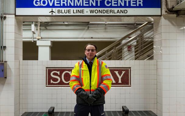 Motorperson Carl Rothenhaus poses below a Government Center sign